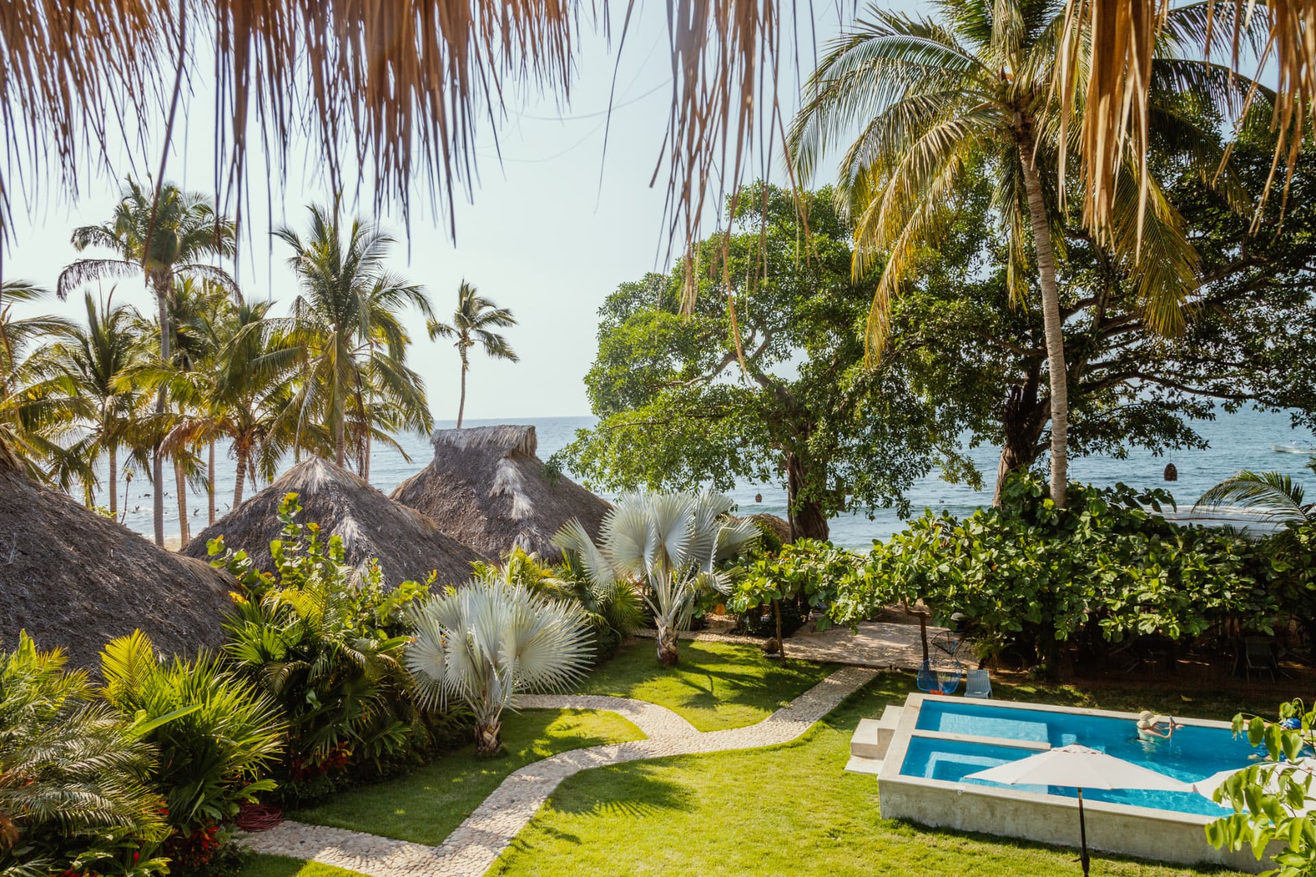 Jardín tropical, palapas y alberca frente al mar en Amaca Beach Retreat, Quimixto