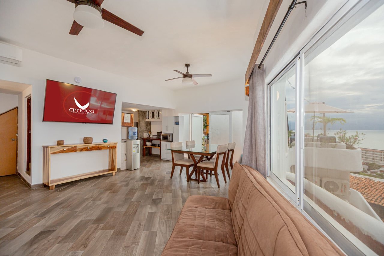 Sala del Penthouse de Amaca con ventanales y vista al mar
